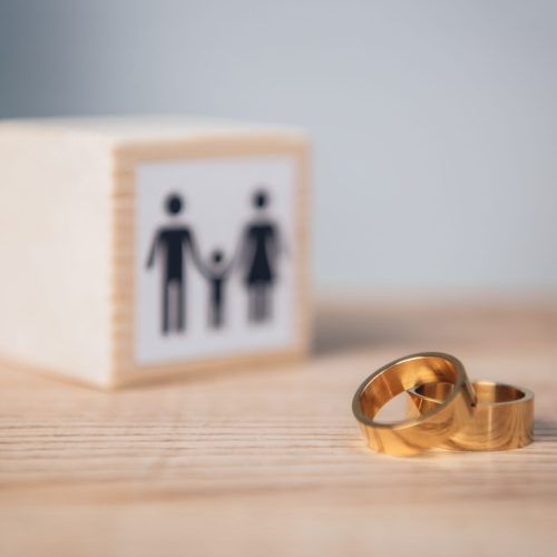 selective focus of golden rings near wooden cube with family