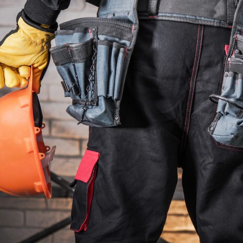 Construction Worker with Orange Hard Hat in a Hand. Industrial Safety Theme.